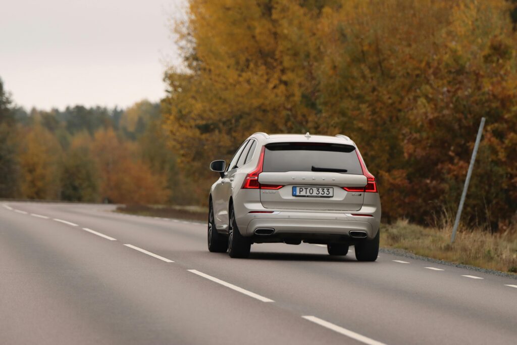 A Volvo car driving on a picturesque autumn road in Axamo, Sweden.